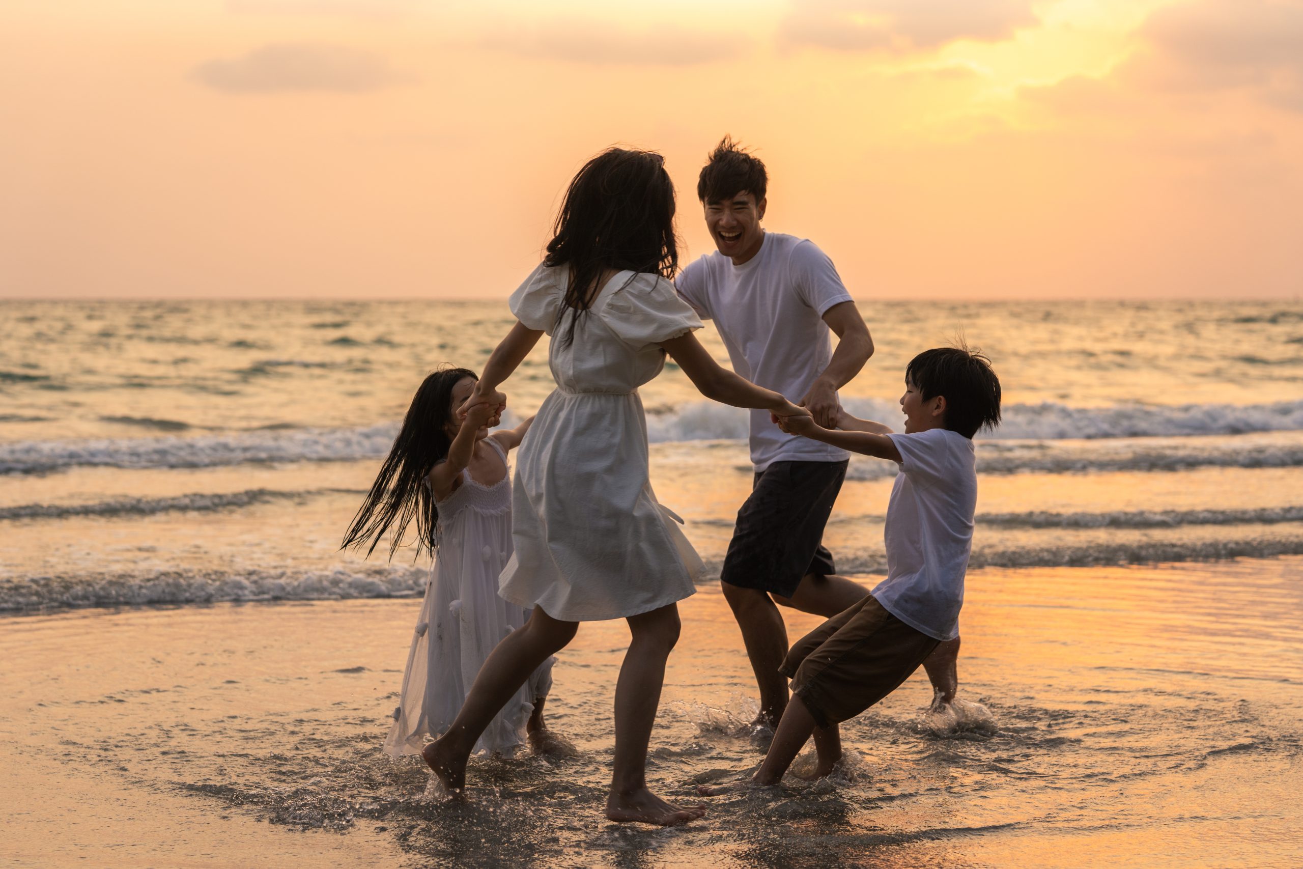Asian young happy family enjoy vacation on beach in the evening. Asian young happy family enjoy vacation on beach in the evening. Dad, mom and kid relax playing together near sea when silhouette sunset. Lifestyle travel holiday vacation summer concept.